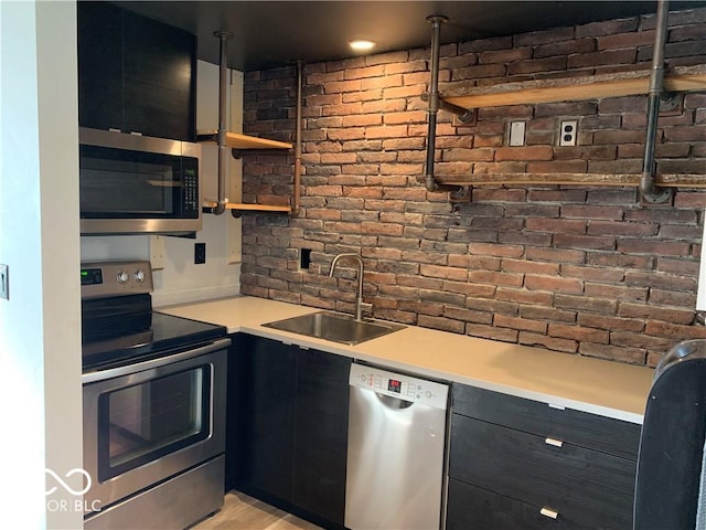 kitchen with brick wall, pendant lighting, stainless steel appliances, and sink