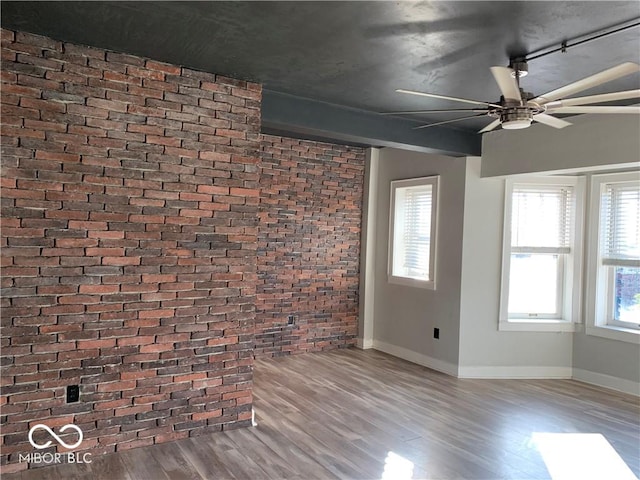 unfurnished living room featuring hardwood / wood-style floors, ceiling fan, plenty of natural light, and brick wall