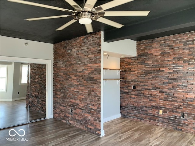 spare room with beamed ceiling, dark hardwood / wood-style flooring, and brick wall