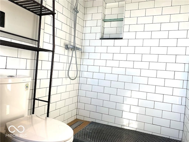 bathroom featuring tiled shower and toilet