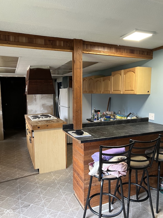 kitchen with kitchen peninsula, light brown cabinetry, a breakfast bar, white appliances, and extractor fan