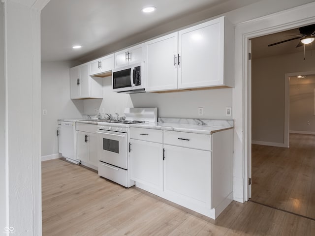 kitchen with light stone countertops, white appliances, ceiling fan, white cabinets, and light hardwood / wood-style floors