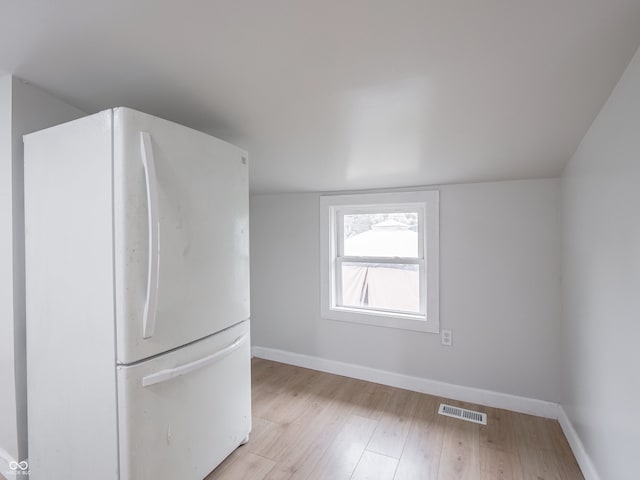 kitchen with white refrigerator, light hardwood / wood-style flooring, and vaulted ceiling