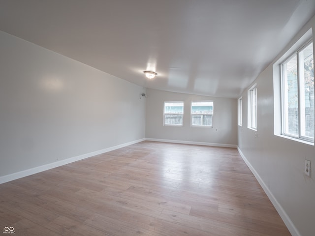 unfurnished room featuring lofted ceiling and light hardwood / wood-style flooring