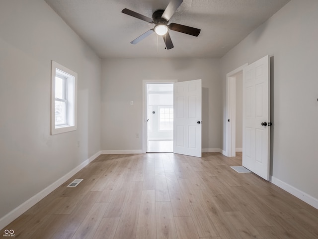 empty room with ceiling fan, light hardwood / wood-style flooring, and a textured ceiling