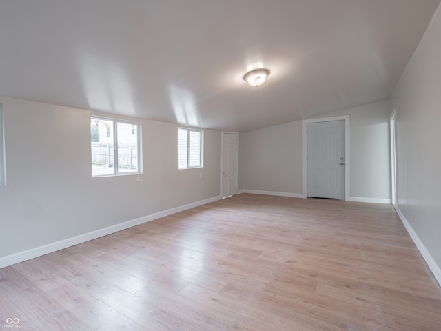 spare room with light hardwood / wood-style flooring and vaulted ceiling