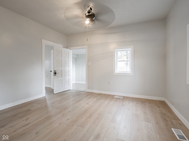 empty room with ceiling fan and light hardwood / wood-style flooring