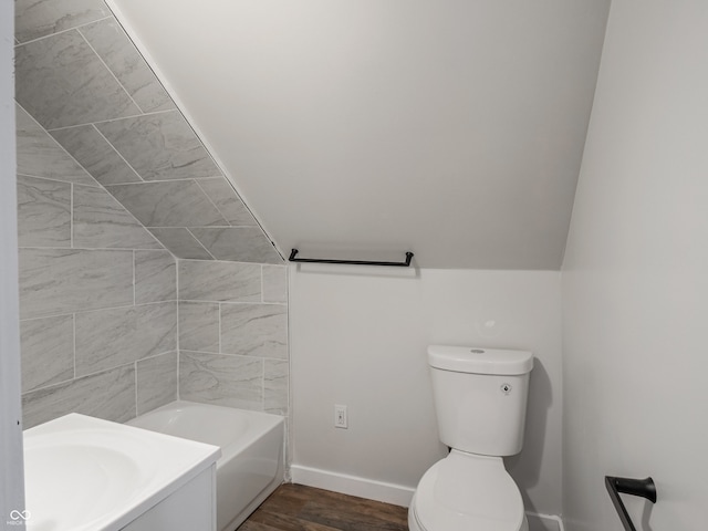 bathroom with a tub to relax in, vanity, vaulted ceiling, hardwood / wood-style flooring, and toilet