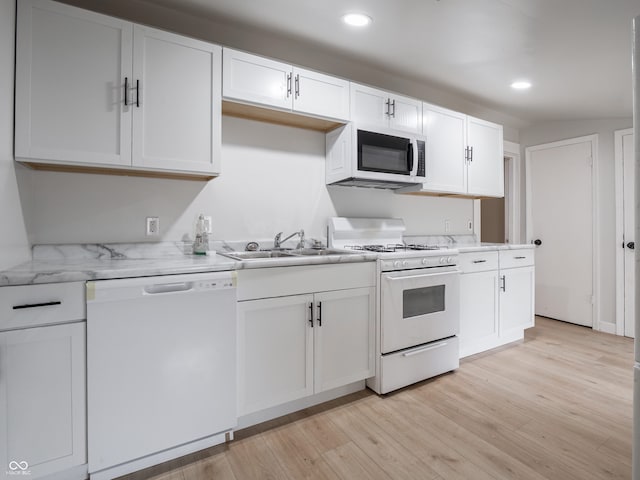 kitchen with white appliances, white cabinets, sink, vaulted ceiling, and light hardwood / wood-style flooring