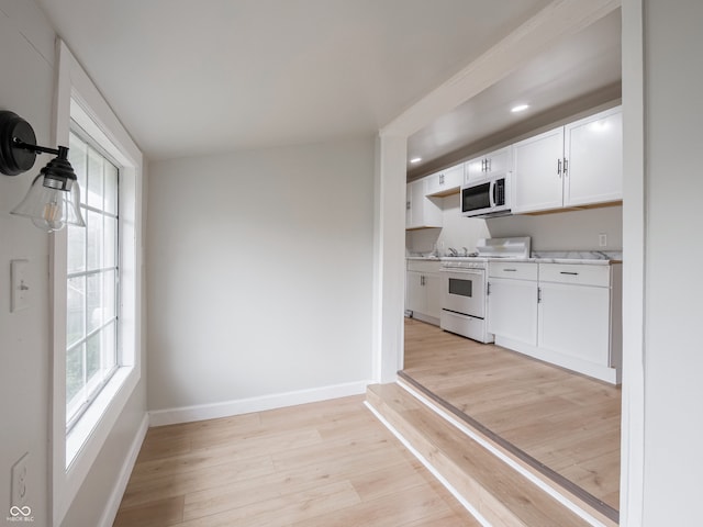 kitchen with white cabinets, a healthy amount of sunlight, white range oven, and light wood-type flooring