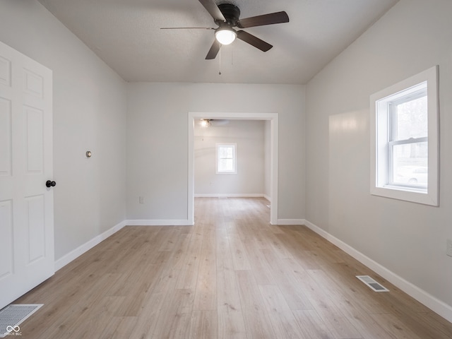 unfurnished room featuring a wealth of natural light, ceiling fan, and light wood-type flooring