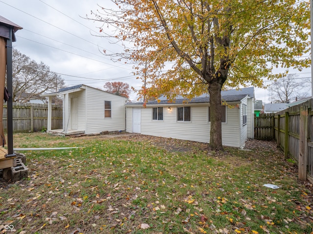 rear view of property featuring a yard and an outdoor structure