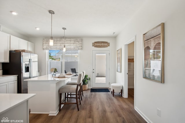 kitchen with stainless steel fridge with ice dispenser, dark hardwood / wood-style floors, white cabinetry, and a wealth of natural light