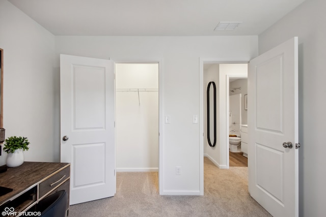 bedroom featuring light colored carpet, a spacious closet, and a closet