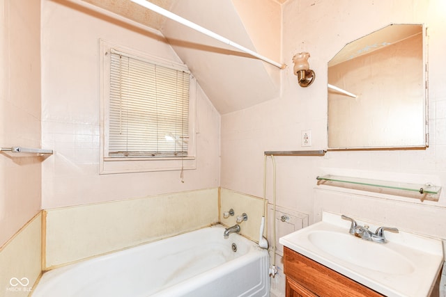 bathroom with vanity, lofted ceiling, and a tub