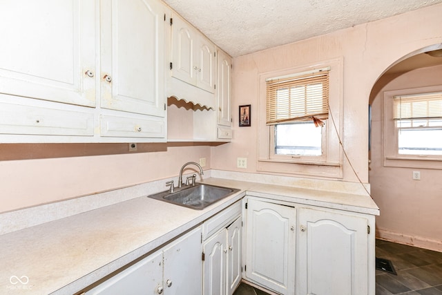 kitchen with white cabinets, a healthy amount of sunlight, sink, and a textured ceiling