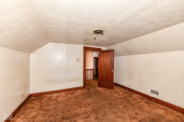 additional living space with dark carpet and lofted ceiling