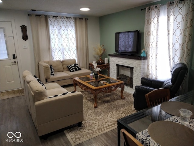 living room featuring a stone fireplace and wood-type flooring