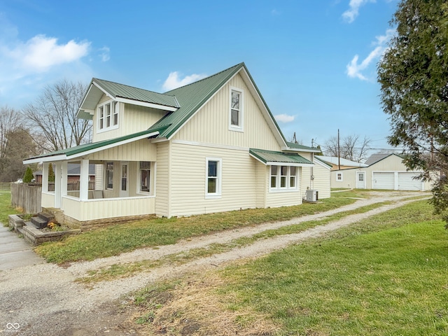 view of side of home with a porch, a yard, and central AC