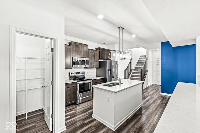 kitchen featuring pendant lighting, a kitchen island with sink, sink, dark hardwood / wood-style flooring, and stainless steel appliances