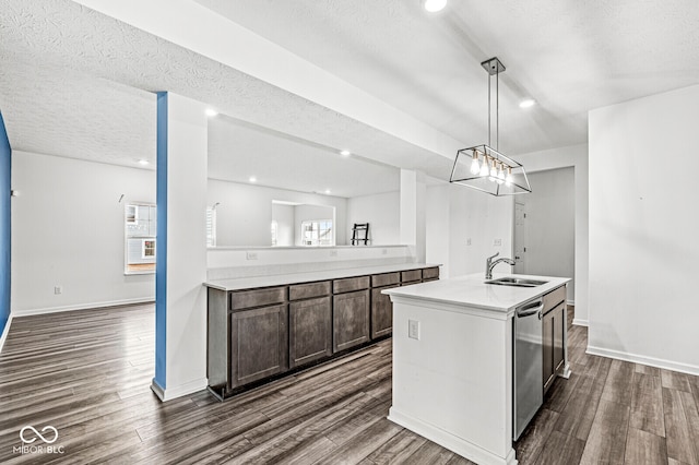 kitchen featuring dark brown cabinetry, dark wood-type flooring, decorative light fixtures, a textured ceiling, and a center island with sink