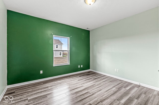 unfurnished room with light hardwood / wood-style floors and a textured ceiling