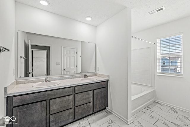 bathroom featuring vanity, a textured ceiling, and bathtub / shower combination