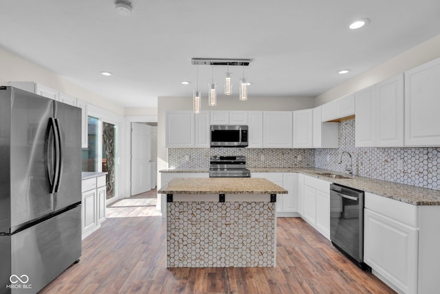 kitchen with stainless steel appliances, sink, light hardwood / wood-style flooring, a center island, and hanging light fixtures