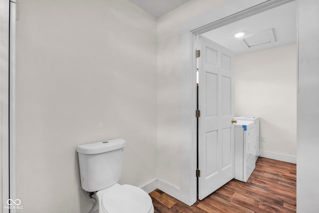 bathroom featuring hardwood / wood-style floors, washer and clothes dryer, and toilet