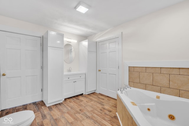 bathroom featuring a bath, vanity, hardwood / wood-style flooring, and toilet