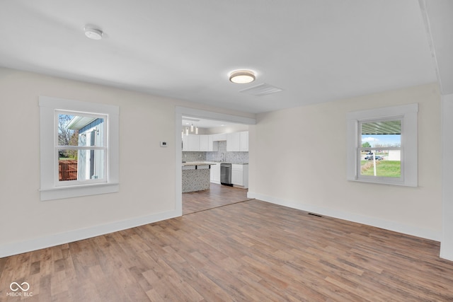 unfurnished living room featuring a wealth of natural light, light hardwood / wood-style flooring, and sink