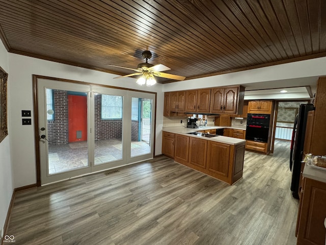 kitchen with ornamental molding, light wood-type flooring, kitchen peninsula, and wooden ceiling