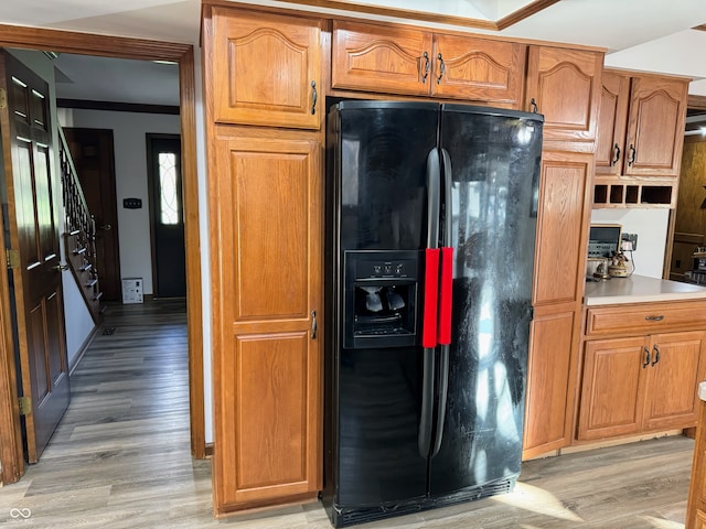 kitchen featuring light wood-type flooring, black fridge, and crown molding