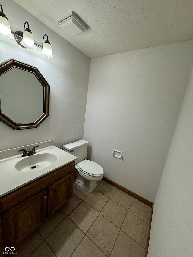 bathroom featuring tile patterned flooring, a textured ceiling, vanity, and toilet