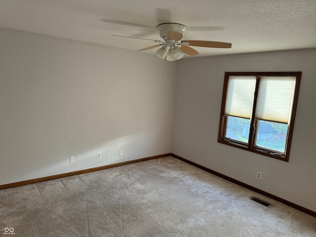 spare room featuring ceiling fan, light colored carpet, and a textured ceiling