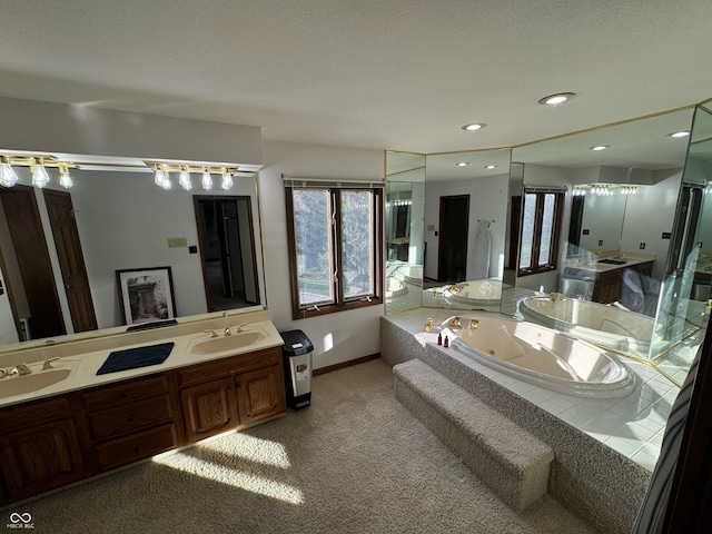 bathroom with tiled tub, vanity, and a textured ceiling