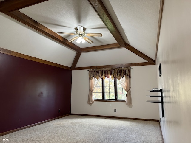 carpeted spare room with a textured ceiling, lofted ceiling with beams, and ceiling fan