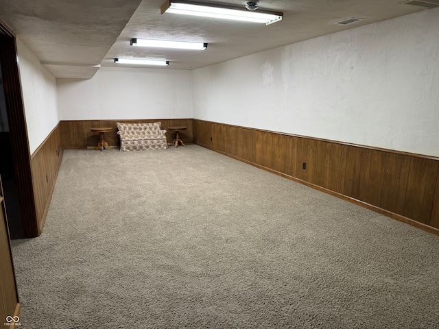 basement featuring light carpet and wooden walls