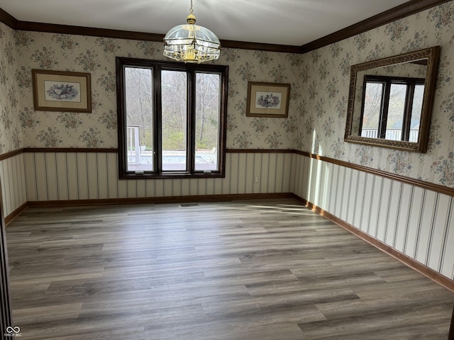 spare room featuring a wealth of natural light, hardwood / wood-style floors, a chandelier, and ornamental molding