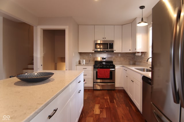 kitchen featuring pendant lighting, dark wood-type flooring, white cabinets, sink, and stainless steel appliances