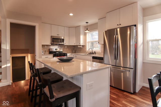 kitchen featuring white cabinetry, a kitchen island, hanging light fixtures, and appliances with stainless steel finishes