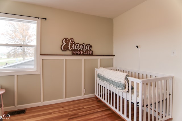 bedroom featuring wood-type flooring and a crib