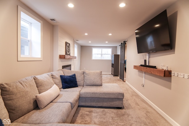 living room with a barn door and light colored carpet