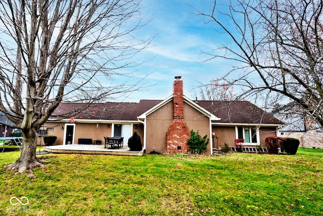 rear view of property featuring a trampoline, a lawn, a chimney, and a patio