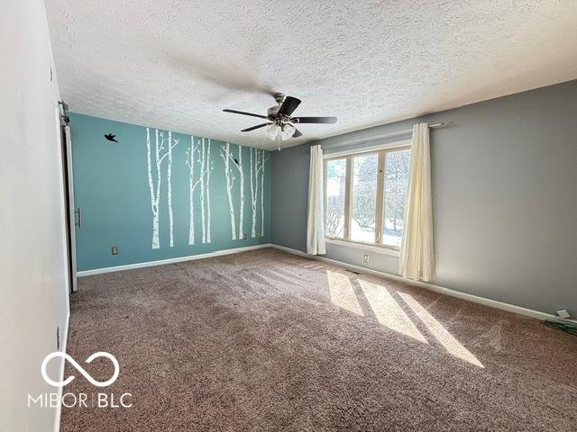 unfurnished room featuring ceiling fan, a textured ceiling, carpet, and baseboards