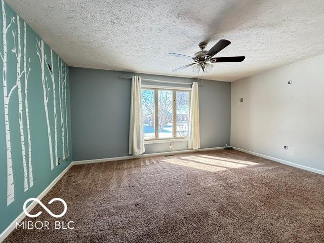 spare room featuring carpet floors, a textured ceiling, baseboards, and a ceiling fan