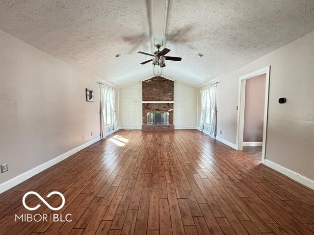 unfurnished living room featuring dark wood-style floors, plenty of natural light, and a brick fireplace