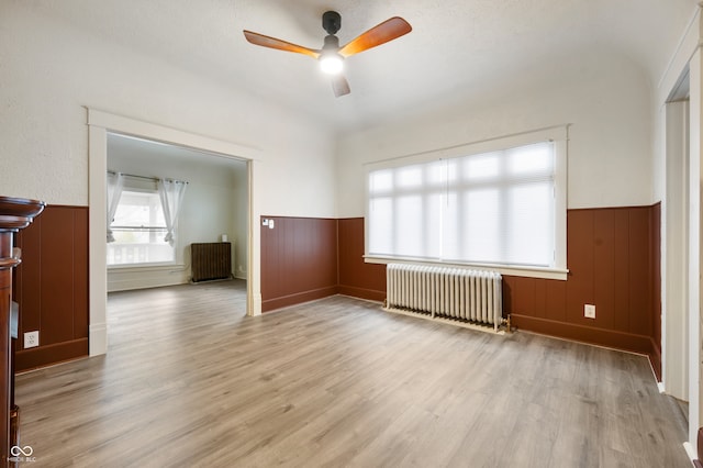 unfurnished room with radiator heating unit, light wood-type flooring, a textured ceiling, and ceiling fan