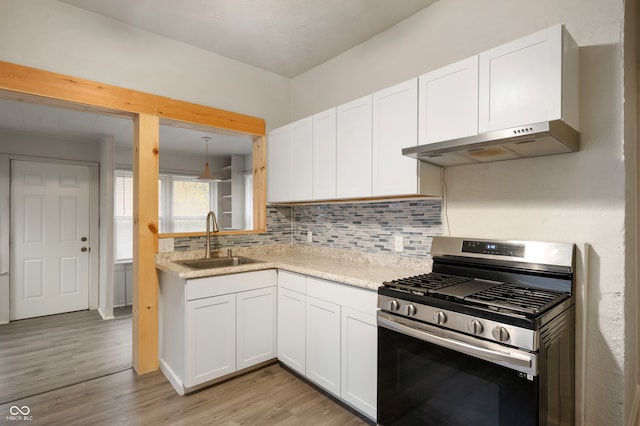 kitchen featuring stainless steel gas range oven, exhaust hood, sink, light hardwood / wood-style floors, and white cabinetry