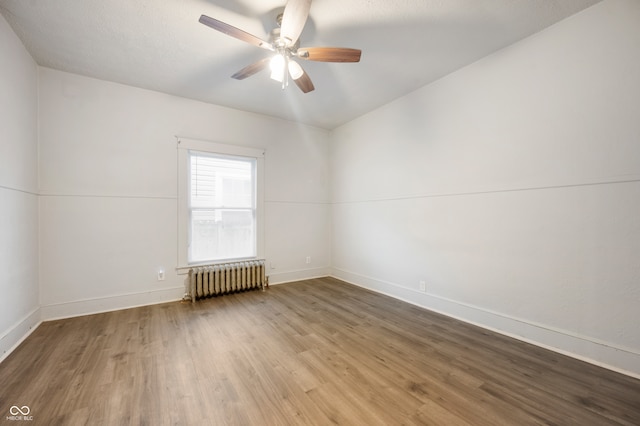 spare room with radiator heating unit, ceiling fan, and hardwood / wood-style floors